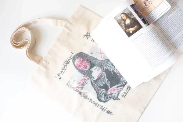 Graffiti-style Mona Lisa tote bag with art book placed on top