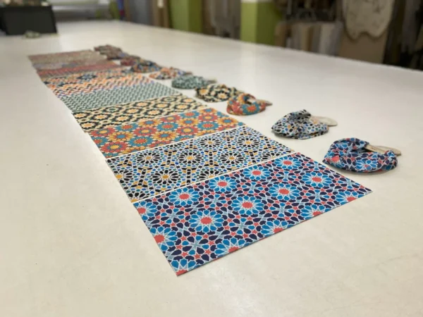 Colorful printed buff fabric samples and folded buffs lined up on a production table