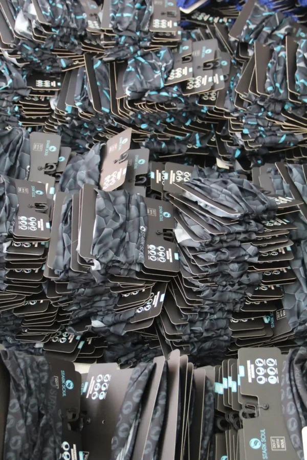 Bulk packed tubular buffs with branded cardboard hangers – production view