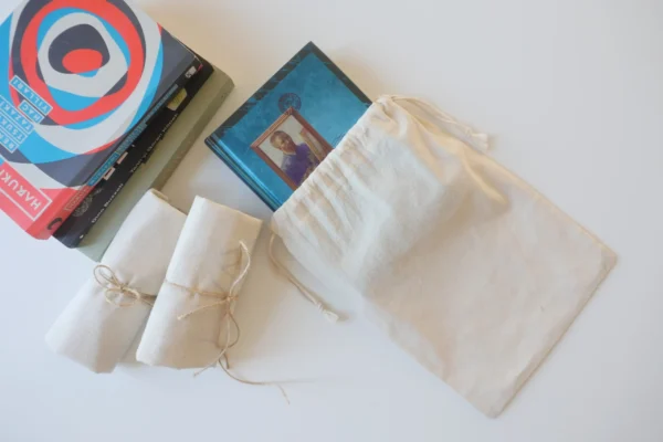 Cotton drawstring pouch with books and rolled gift items on white background