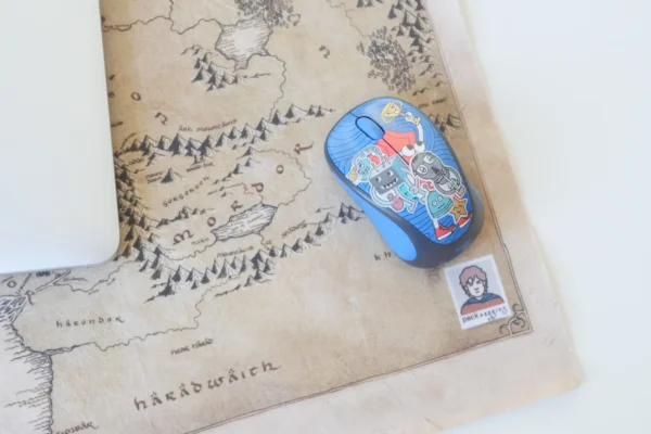Close-up of a fantasy-themed large mouse pad with a colorful mouse and packaging logo visible
