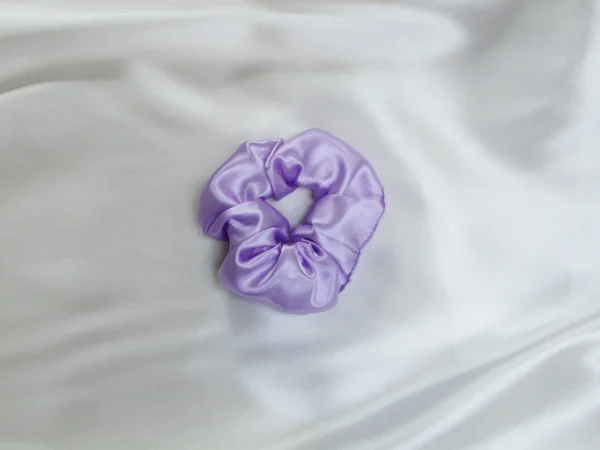 Lavender satin scrunchy placed on a white satin fabric