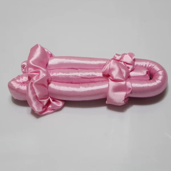 Pink satin heatless curling rod with soft bows, displayed on a plain surface