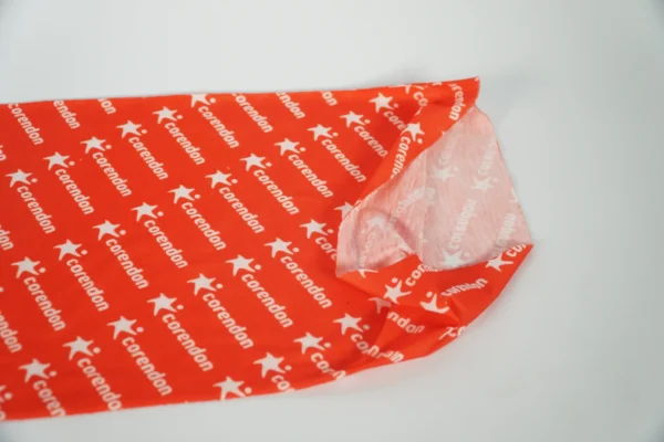 Detailed close-up of custom logo on red buff – promotional textile by Textile Promos