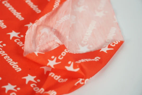 Close-up of logo print on red promotional buff – Textile Promos