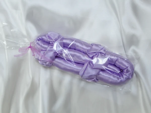 Lavender satin heatless curling rod in transparent gift packaging on satin background