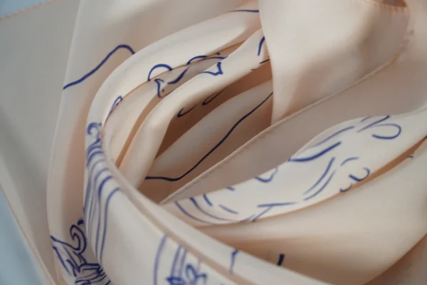 Close-up side view of rolled square scarf with printed detail – Textile Promos