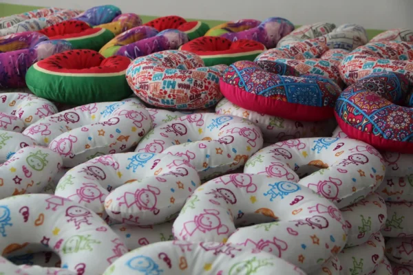 Bulk assortment of colorful custom-printed travel pillows with various patterns – Textile Promos