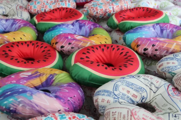 Close-up of watermelon and rainbow-themed custom travel pillows – Textile Promos