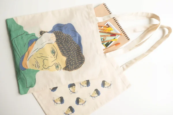 Canvas tote bags with Van Gogh face illustration and art supplies inside