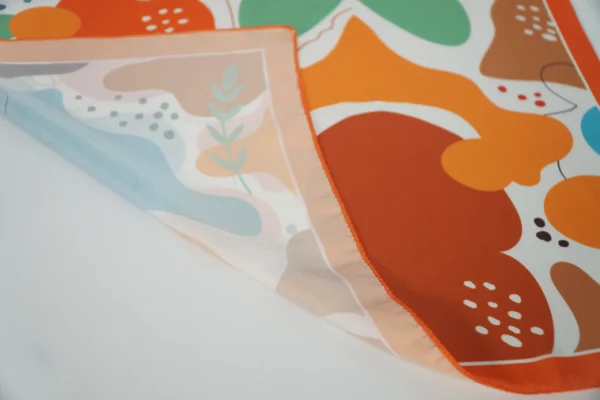 Extreme close-up of smooth stitching on vivid patterned square scarf – Textile Promos
