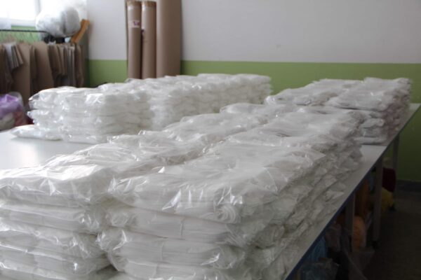Bulk stock of disposable VR hygiene masks packaged and stacked in a textile production facility